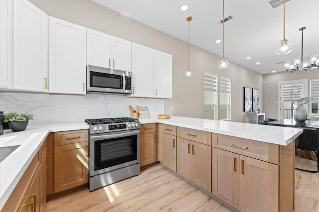 kitchen featuring stainless steel appliances, visible vents, light wood-style flooring, a peninsula, and light countertops