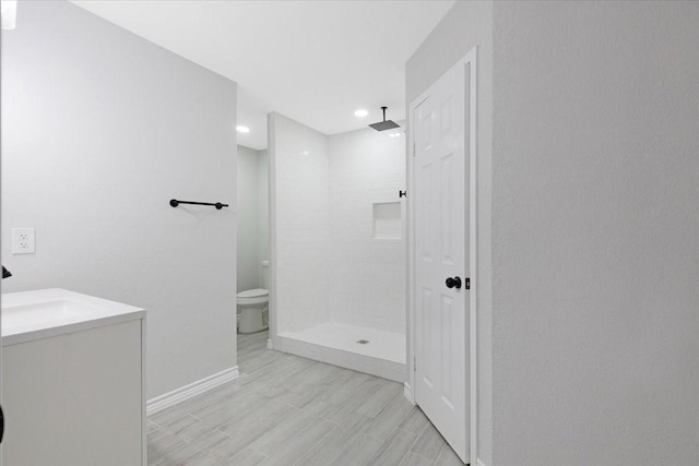 bathroom featuring vanity, toilet, and tiled shower