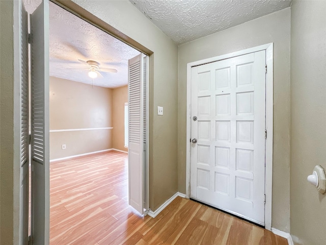 foyer with ceiling fan, light hardwood / wood-style flooring, and a textured ceiling