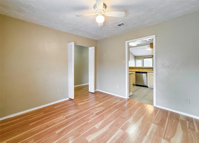 empty room featuring ceiling fan, a textured ceiling, and light wood-type flooring