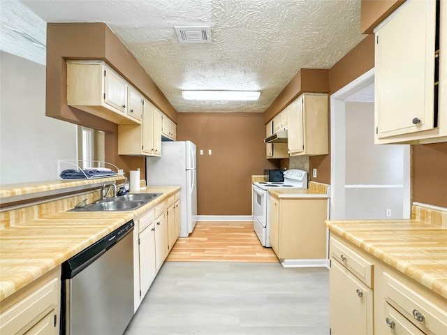 kitchen with sink, light hardwood / wood-style flooring, a textured ceiling, white appliances, and cream cabinetry