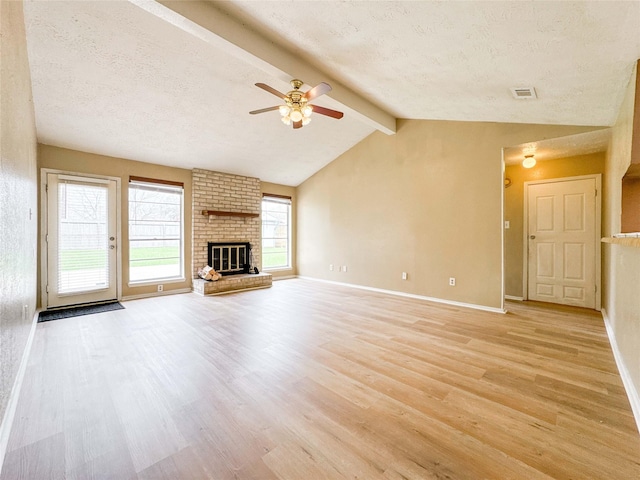 unfurnished living room with lofted ceiling with beams, a textured ceiling, visible vents, light wood-type flooring, and a brick fireplace