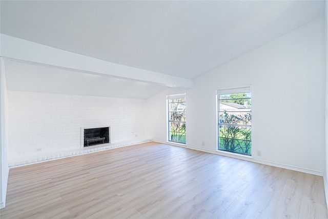 unfurnished living room with lofted ceiling with beams, a brick fireplace, and light hardwood / wood-style floors