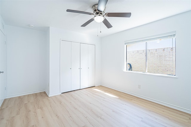 unfurnished bedroom featuring ceiling fan, a closet, and light wood-type flooring