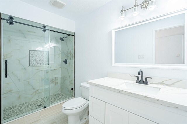 bathroom featuring vanity, an enclosed shower, and toilet