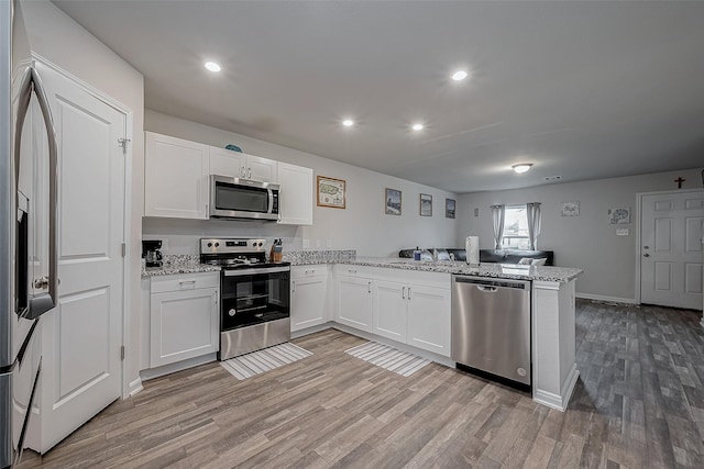 kitchen featuring appliances with stainless steel finishes, kitchen peninsula, white cabinets, light hardwood / wood-style floors, and light stone counters