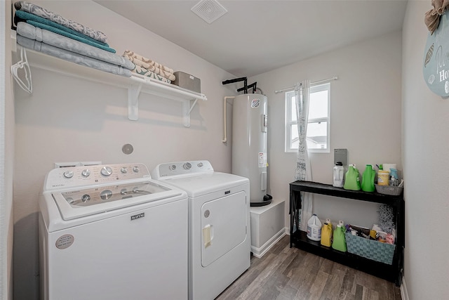 clothes washing area with hardwood / wood-style flooring, electric water heater, and washer and clothes dryer