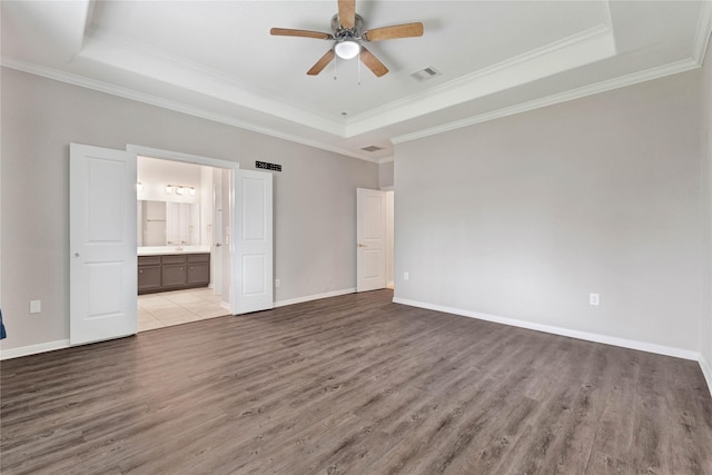 unfurnished bedroom featuring connected bathroom, crown molding, light hardwood / wood-style floors, and a raised ceiling