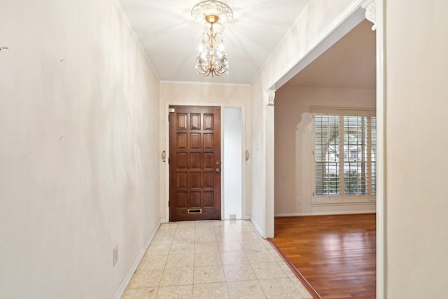 entryway with light tile patterned flooring, a notable chandelier, and crown molding