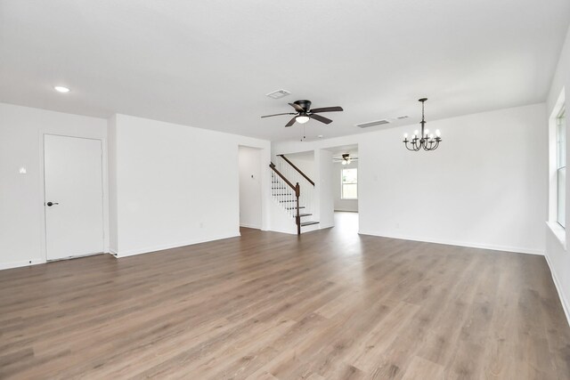 unfurnished living room featuring wood-type flooring and ceiling fan with notable chandelier