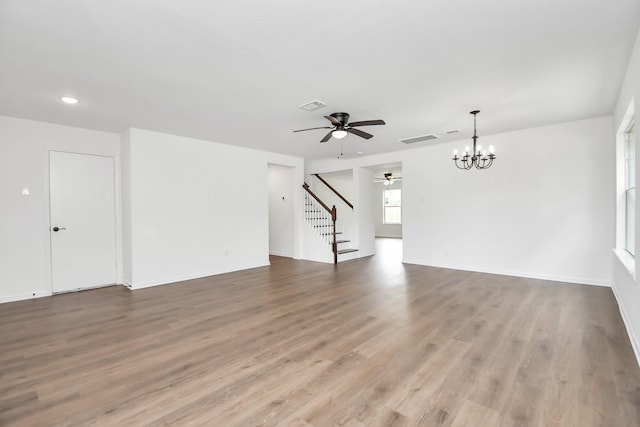 unfurnished living room with ceiling fan with notable chandelier and hardwood / wood-style floors