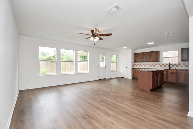 kitchen with wood-type flooring, a center island, sink, and backsplash