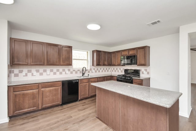 kitchen with tasteful backsplash, sink, a center island, light hardwood / wood-style floors, and black appliances