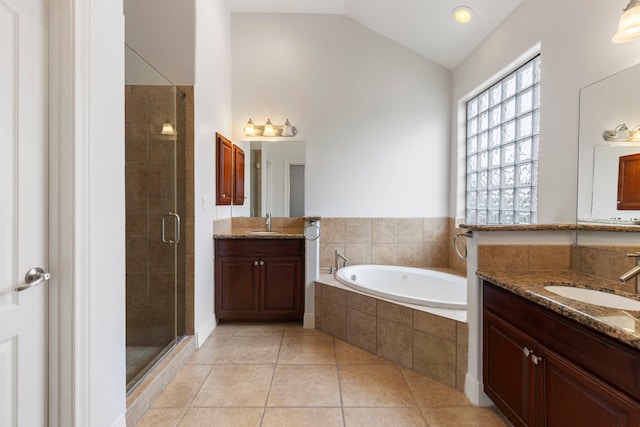 bathroom with tile patterned floors, shower with separate bathtub, vaulted ceiling, and vanity