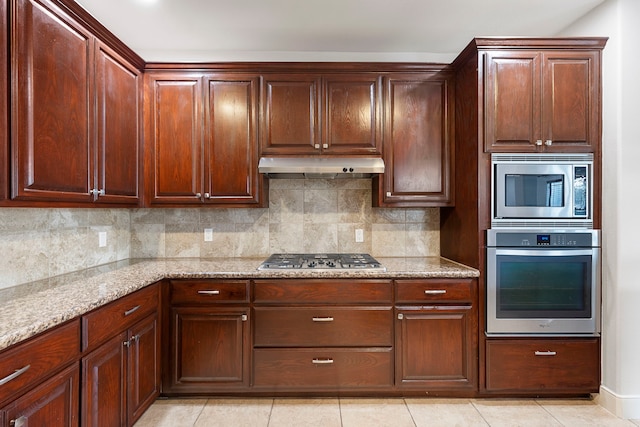 kitchen featuring stainless steel appliances, light tile patterned floors, light stone counters, and decorative backsplash