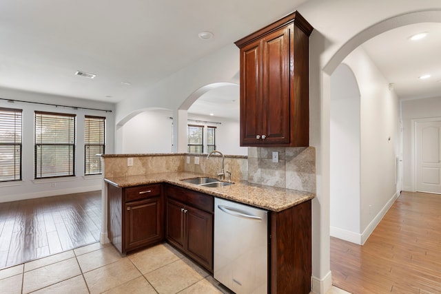 kitchen featuring light stone countertops, sink, stainless steel dishwasher, and kitchen peninsula