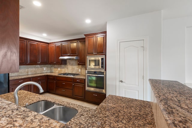 kitchen featuring light tile patterned flooring, sink, decorative backsplash, dark stone counters, and stainless steel appliances