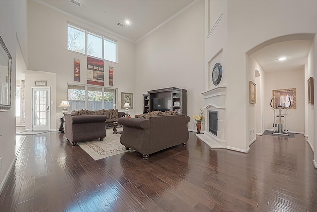 living room with hardwood / wood-style flooring, ornamental molding, a healthy amount of sunlight, and a high ceiling