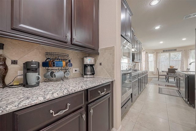 kitchen featuring tasteful backsplash, sink, oven, light tile patterned floors, and light stone countertops