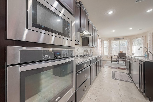 kitchen featuring sink, appliances with stainless steel finishes, tasteful backsplash, light stone countertops, and light tile patterned flooring