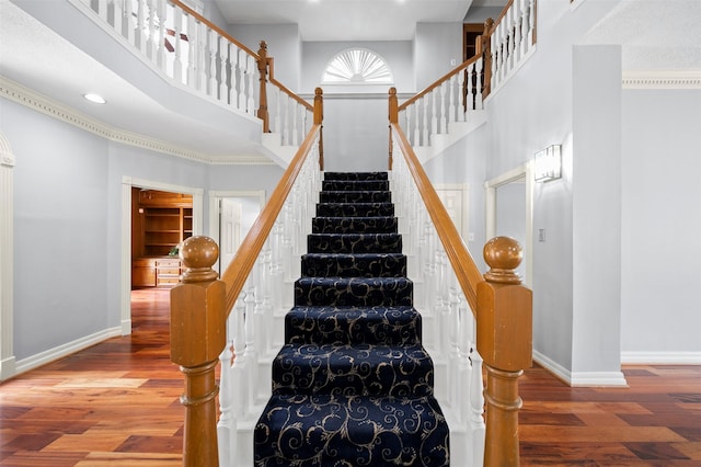 stairs with a high ceiling and hardwood / wood-style floors