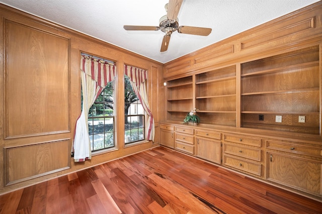 unfurnished office featuring a textured ceiling, dark wood-type flooring, ornamental molding, and ceiling fan