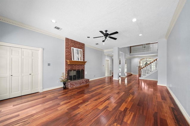 unfurnished living room featuring a brick fireplace, crown molding, wood-type flooring, and ceiling fan