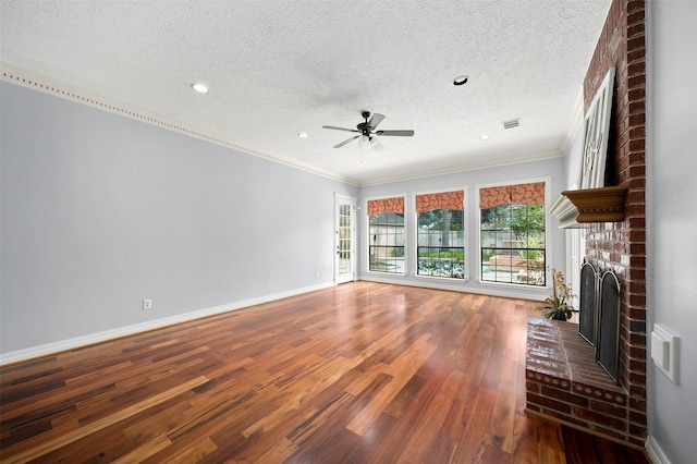 unfurnished living room featuring hardwood / wood-style floors, ornamental molding, ceiling fan, a brick fireplace, and a textured ceiling