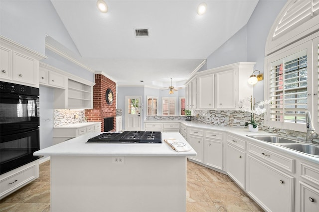 kitchen featuring sink, white cabinetry, black double oven, a kitchen island, and stainless steel gas stovetop