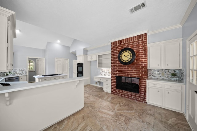 kitchen featuring black appliances, white cabinets, backsplash, kitchen peninsula, and a brick fireplace