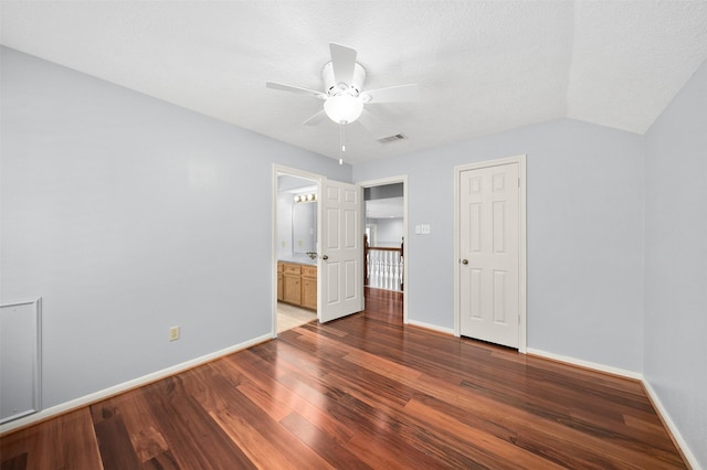 unfurnished bedroom with ceiling fan, hardwood / wood-style floors, connected bathroom, a textured ceiling, and vaulted ceiling