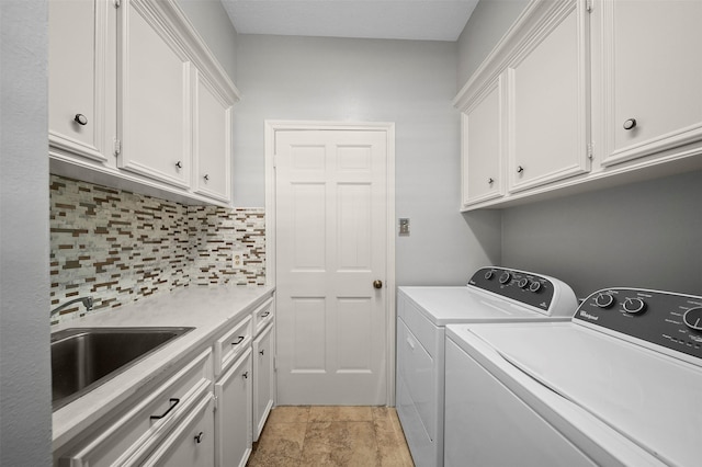 clothes washing area with sink, cabinets, and washer and dryer