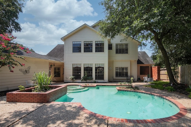 rear view of property featuring a pool with hot tub and a patio