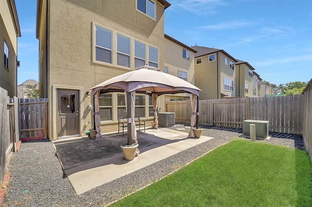 rear view of house with central AC unit, a gazebo, a patio, and a yard