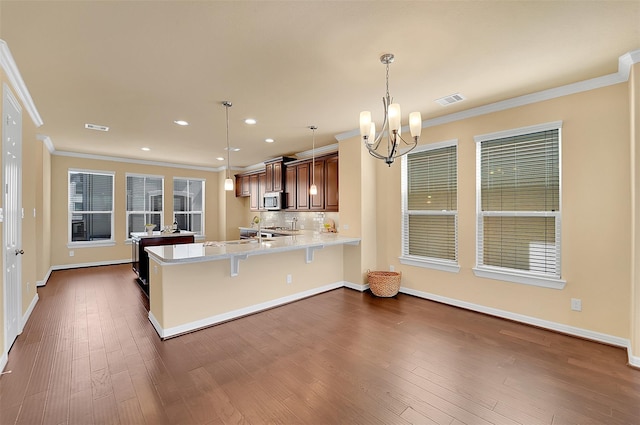 kitchen with pendant lighting, a breakfast bar area, dark hardwood / wood-style flooring, kitchen peninsula, and light stone countertops