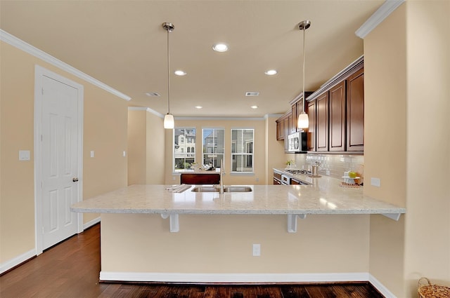 kitchen featuring decorative light fixtures, sink, a kitchen breakfast bar, and kitchen peninsula