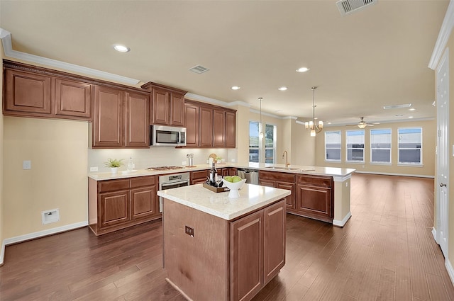 kitchen featuring pendant lighting, sink, stainless steel appliances, dark hardwood / wood-style flooring, and kitchen peninsula