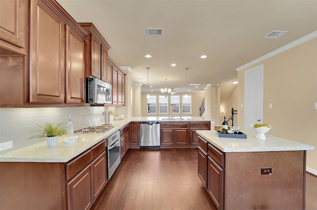 kitchen featuring hanging light fixtures, ornamental molding, kitchen peninsula, stainless steel appliances, and light stone countertops