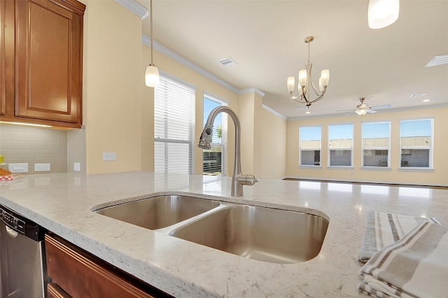 kitchen with light stone countertops, sink, stainless steel dishwasher, and pendant lighting