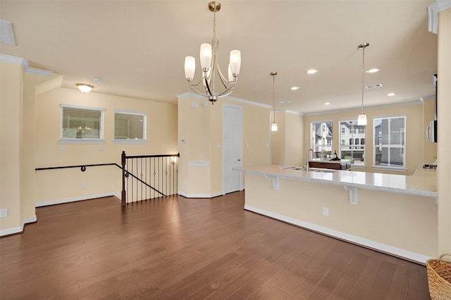 kitchen featuring dark hardwood / wood-style flooring, hanging light fixtures, ornamental molding, and a breakfast bar