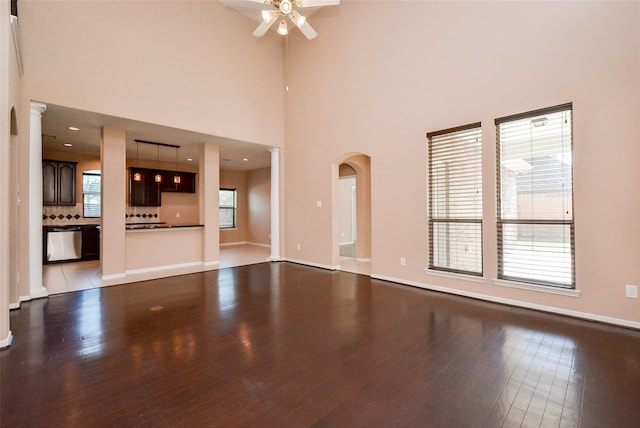 unfurnished living room with ceiling fan, a wealth of natural light, light hardwood / wood-style floors, and a high ceiling