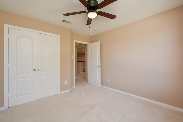 unfurnished bedroom featuring light colored carpet, a closet, and ceiling fan