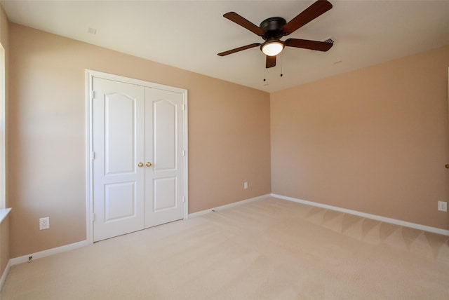 unfurnished bedroom with light colored carpet, ceiling fan, and a closet