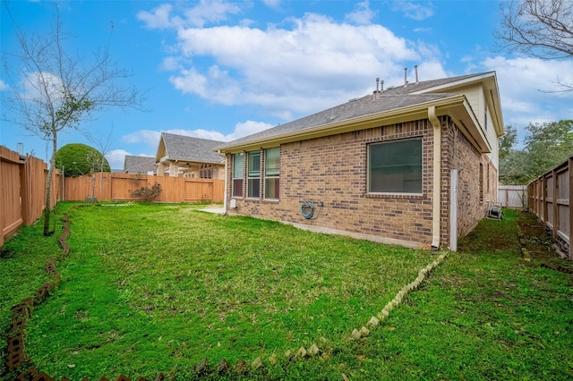 back of property featuring brick siding, a lawn, and a fenced backyard