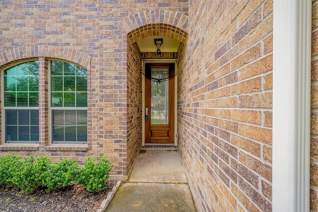 view of exterior entry featuring brick siding