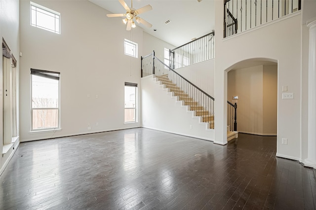 unfurnished living room with a ceiling fan, dark wood finished floors, stairway, and baseboards