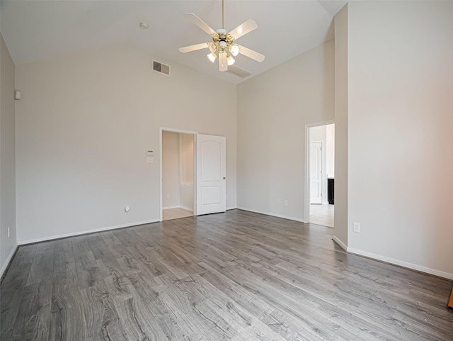 spare room featuring light wood finished floors, visible vents, a ceiling fan, high vaulted ceiling, and baseboards