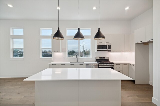 kitchen with pendant lighting, sink, a center island, and appliances with stainless steel finishes