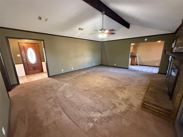 unfurnished living room with crown molding, ceiling fan, lofted ceiling with beams, a brick fireplace, and light colored carpet