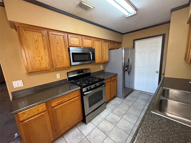 kitchen with sink, crown molding, light tile patterned floors, appliances with stainless steel finishes, and a textured ceiling